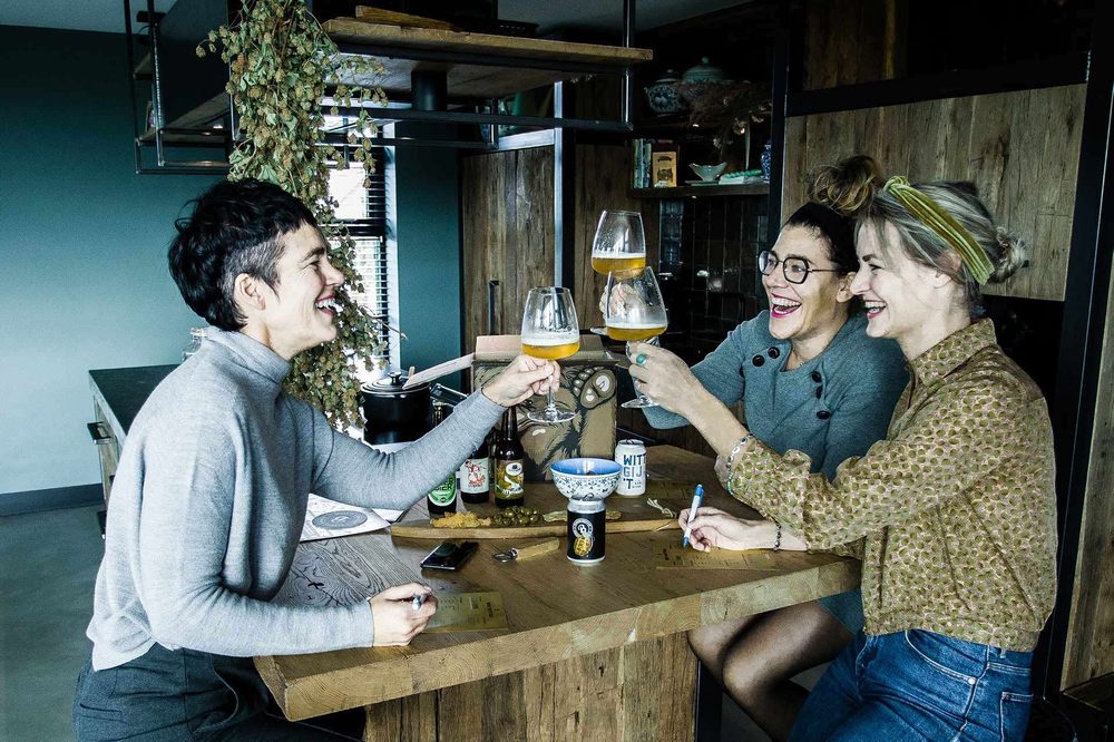Drie vriendinnen proosten aan tafel met bier uit een Beer in a Box